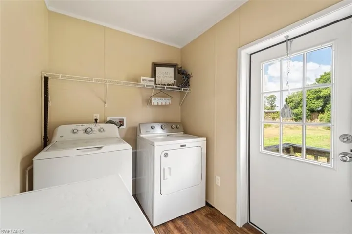 Laundry area with a healthy amount of sunlight, dark wood-type flooring, washer and clothes dryer, and washer hookup