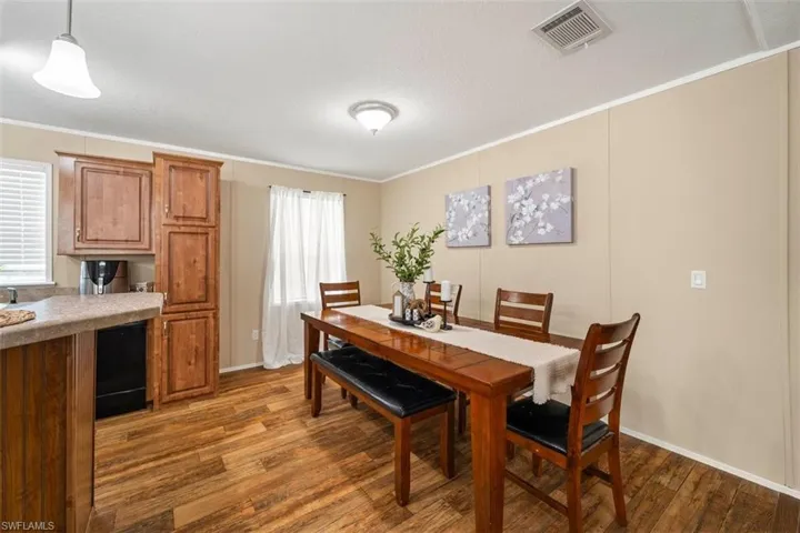 Dining room with dark wood-type flooring and crown molding