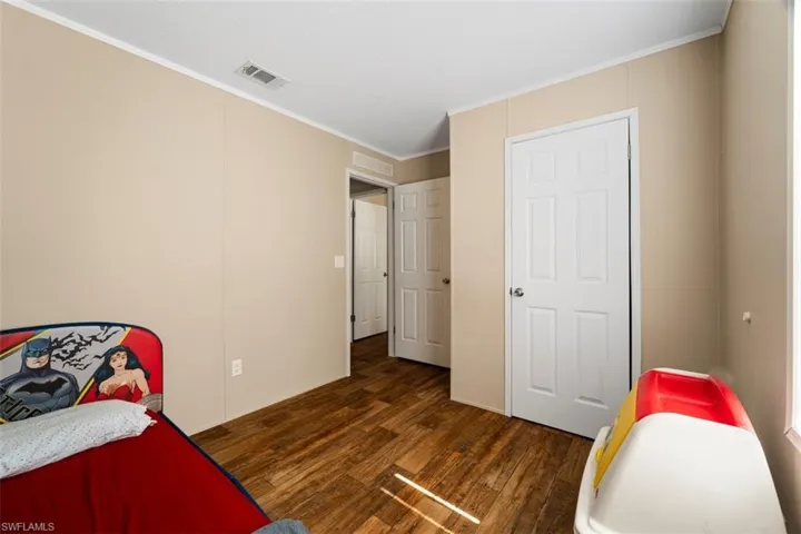 Bedroom with ornamental molding and dark wood-type flooring