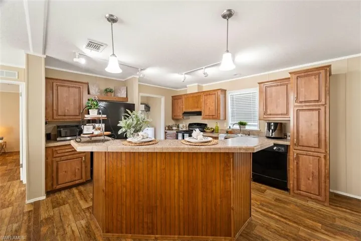 Kitchen featuring dark hardwood / wood-style floors, extractor fan, black appliances, track lighting, and a kitchen island