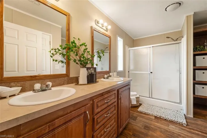 Bathroom featuring crown molding, an enclosed shower, dual vanity, and hardwood / wood-style floors