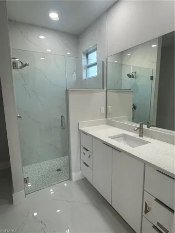 Bathroom featuring tile floors, a shower with shower door, and vanity