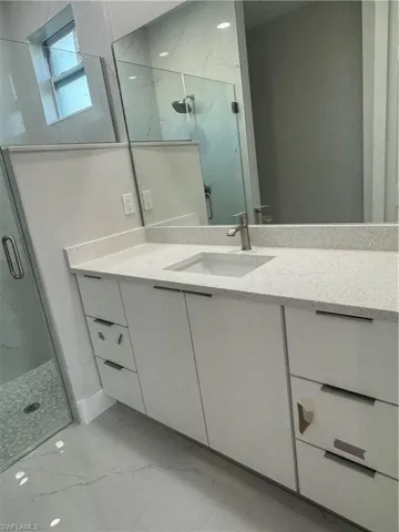 Bathroom featuring an enclosed shower, tile floors, and large vanity