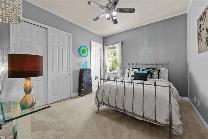 Carpeted bedroom featuring ceiling fan and a closet