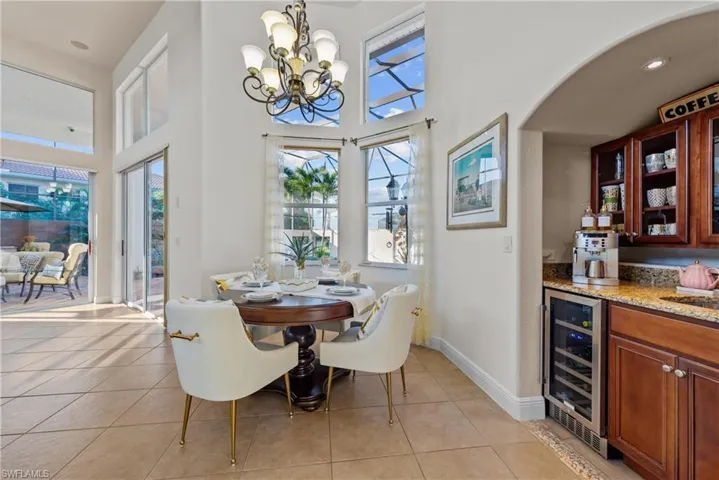 Tiled dining space with indoor wet bar, a towering ceiling, wine cooler, and a chandelier