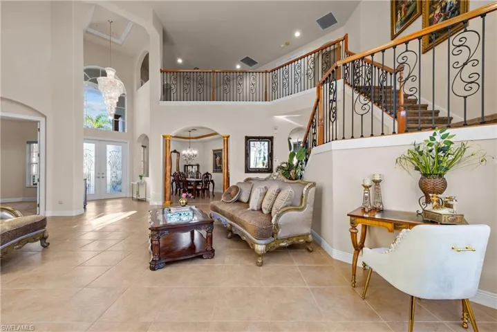 Living room featuring a chandelier, a high ceiling, light tile patterned floors, and french doors