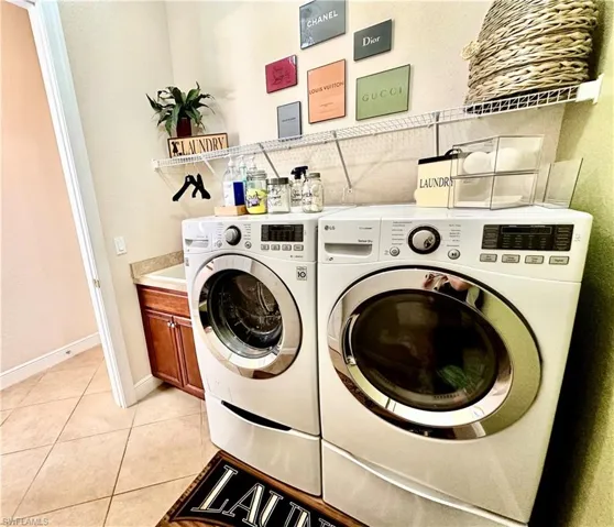 Washroom with light tile patterned flooring, cabinets, and separate washer and dryer