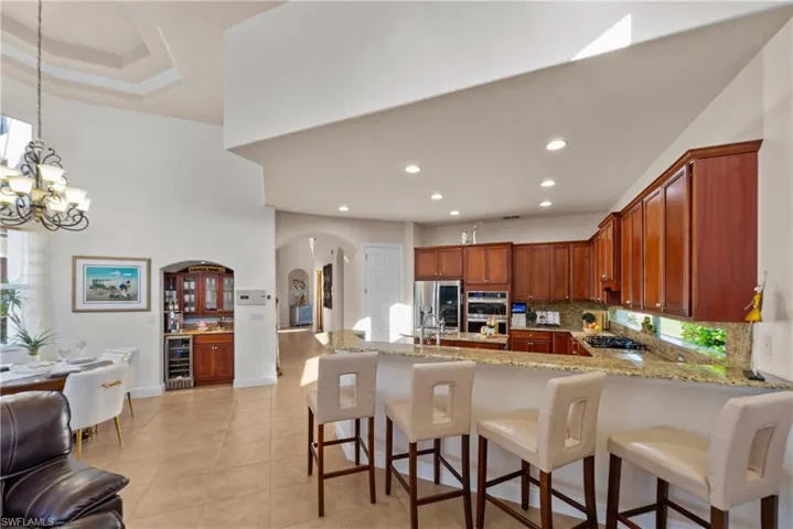 Kitchen with pendant lighting, wine cooler, decorative backsplash, appliances with stainless steel finishes, and a healthy amount of sunlight
