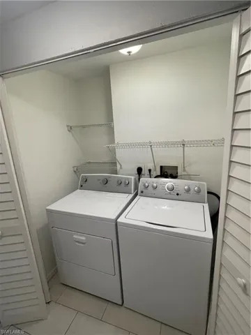 Laundry room with washing machine and clothes dryer and light tile patterned floors