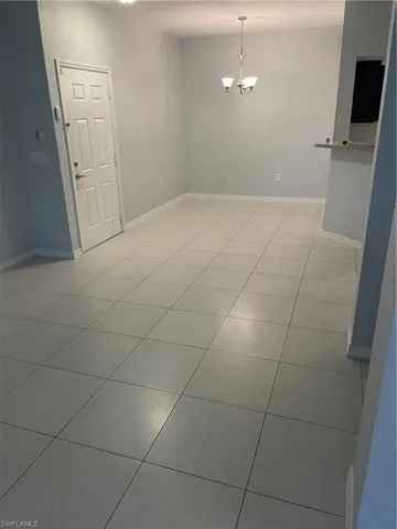 Unfurnished room featuring baseboards and a chandelier