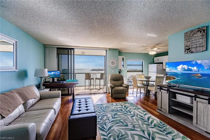 Living room with ceiling fan, a textured ceiling, and dark hardwood / wood-style flooring