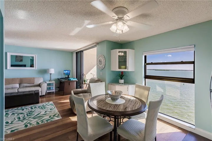 Dining room featuring ceiling fan, dark hardwood / wood-style floors, a textured ceiling, and a water view