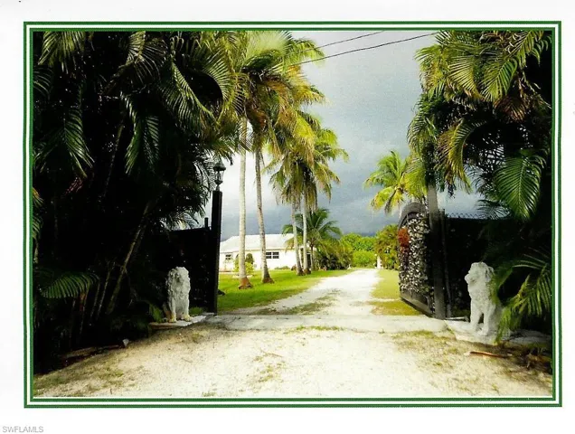 Gated entrance with decorative lion sculptures and a gravel drive