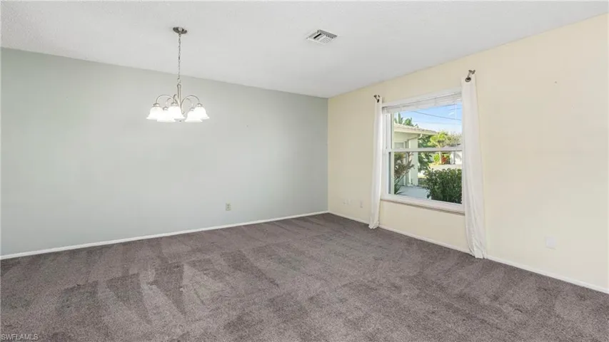Spare room with suspended lighting, dark colored carpet, and a textured ceiling