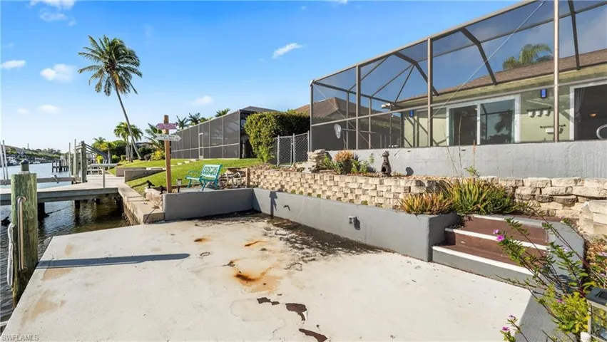 View of patio / terrace featuring glass enclosure, a water view, a sunroom, and a boat dock