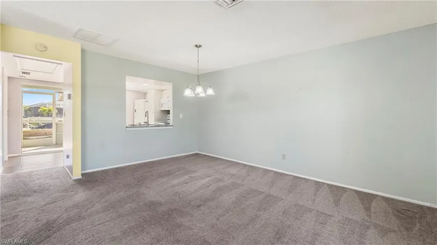 Unfurnished room featuring a chandelier, dark carpet, and a textured ceiling