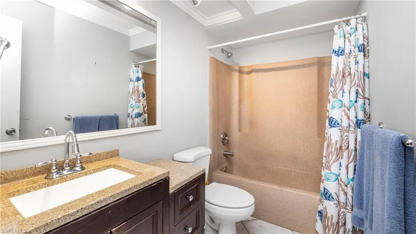 Bathroom with vanity, shower / bath combination with curtain, and ornamental molding
