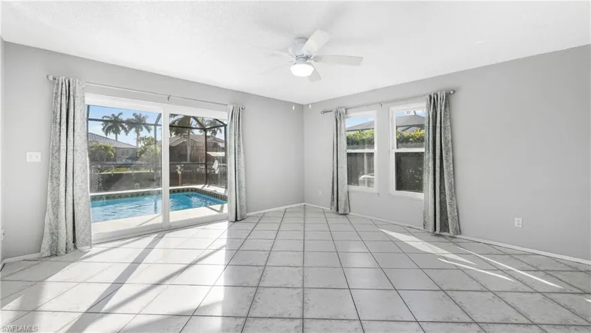 Empty room featuring ceiling fan, a sunroom, light tile patterned floors, and a textured ceiling