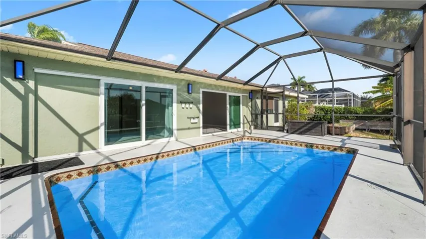 Outdoor pool with a patio, a sunroom, and glass enclosure
