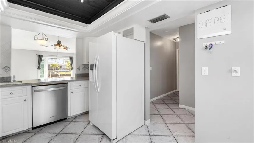 Kitchen featuring white refrigerator with ice dispenser, white cabinets, dishwasher, crown molding, and a ceiling fan