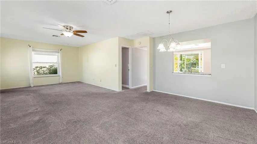 Carpeted spare room with a chandelier and a ceiling fan