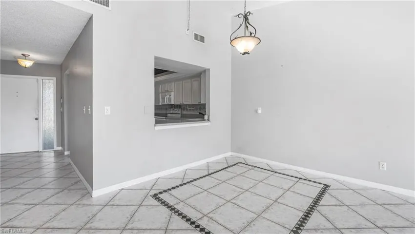 Unfurnished dining area with light tile patterned floors and a high textured ceiling