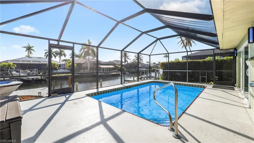 Swimming pool with a lanai, a sunroom, a water view, a patio area, and a residential view