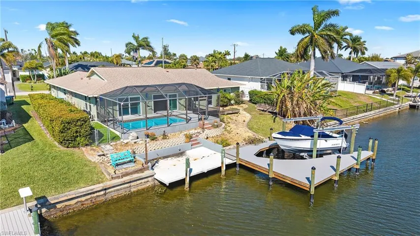 Dock with an outdoor pool, a lanai, boat lift, a water view, and a sunroom