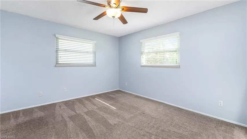 Unfurnished room featuring dark carpet and a ceiling fan