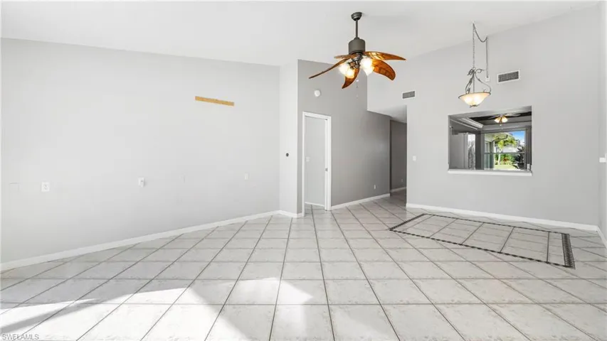 Empty room featuring a ceiling fan and lofted ceiling