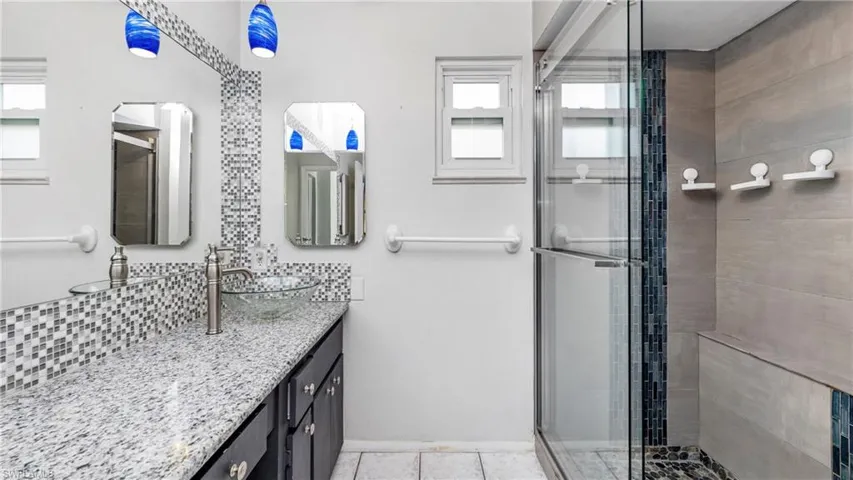 Bathroom with vanity, a stall shower, and decorative backsplash