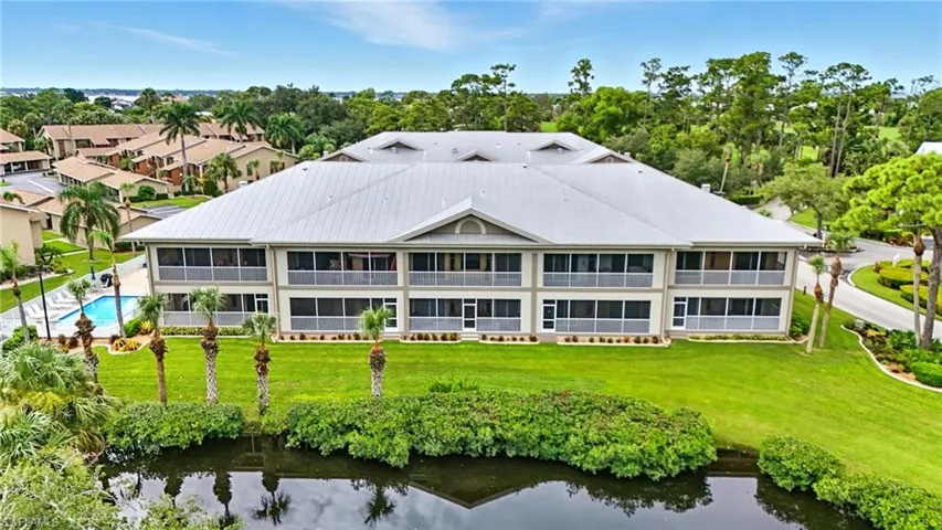Back of property featuring a water view, a yard, and view of scattered trees