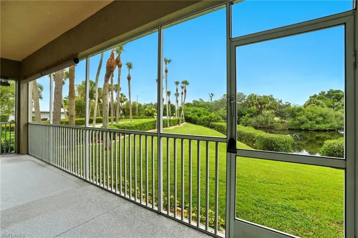 Unfurnished sunroom with view of scattered trees and a water view