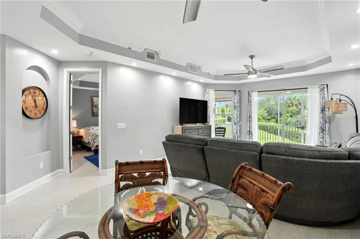 Living room featuring crown molding, a tray ceiling, recessed lighting, ceiling fan, and light wood-type flooring