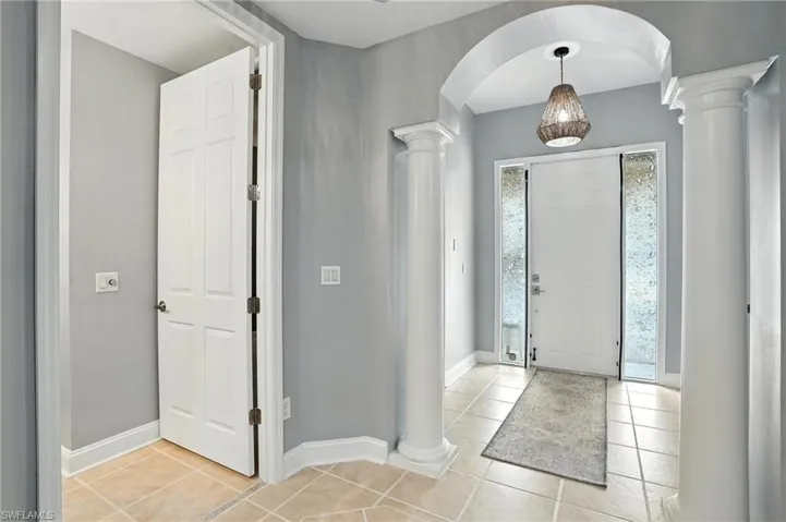 Entrance foyer featuring light tile patterned floors, arched walkways, and decorative columns