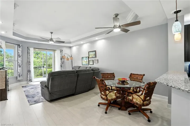 Dining area featuring a raised ceiling, ornamental molding, a ceiling fan, light wood finished floors, and recessed lighting