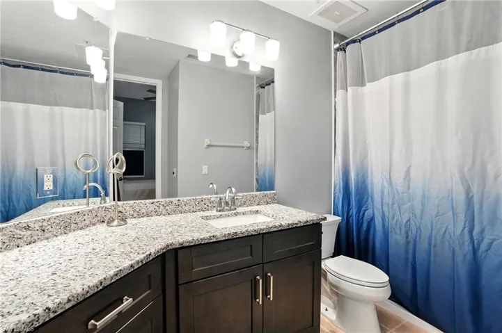 Full bath with vanity, light tile patterned flooring, and curtained shower