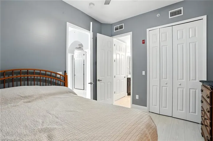Bedroom featuring a closet, ceiling fan, light wood-style floors, and arched walkways