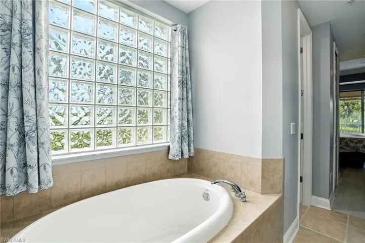 Full bath with a bath, light tile patterned floors, and ensuite bath