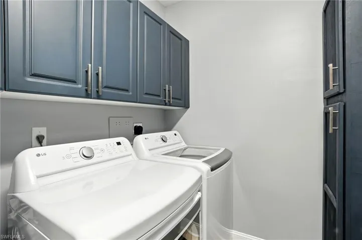 Washroom featuring cabinet space and independent washer and dryer