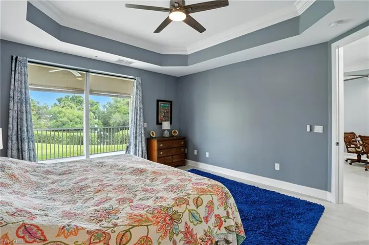 Bedroom featuring a tray ceiling, ornamental molding, access to outside, and wood finished floors