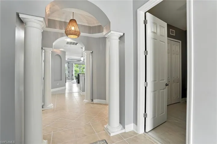 Hall featuring arched walkways and light tile patterned floors