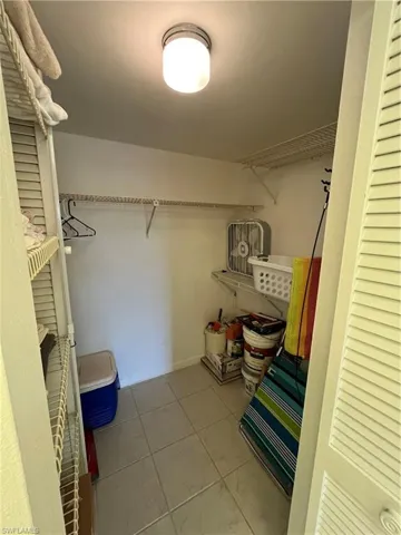 Walk in closet in primary bathroom with light tile patterned flooring