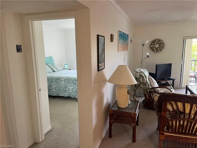Hall with carpet, a textured ceiling, and ornamental molding
