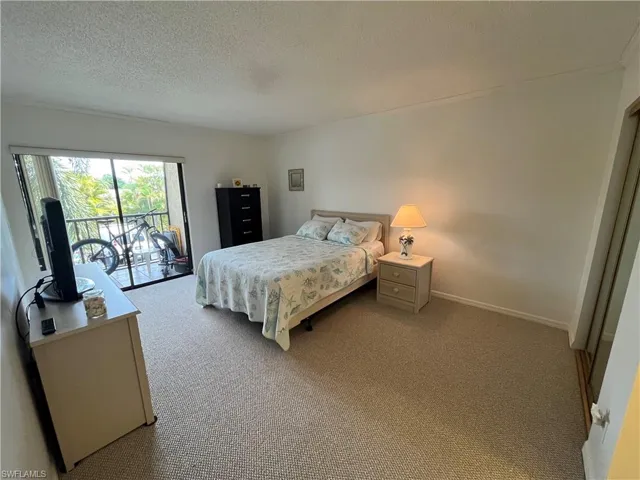 Bedroom with access to exterior, light colored carpet, and a textured ceiling