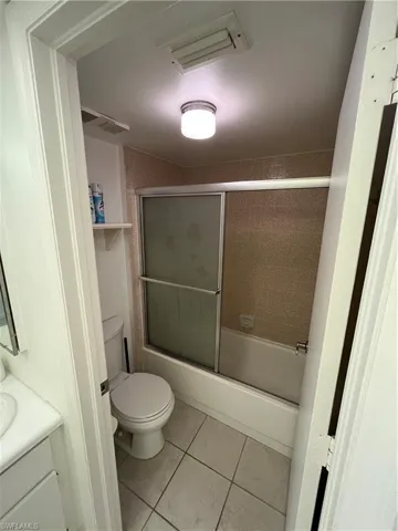 Full bathroom featuring vanity, bath / shower combo with glass door, and light tile patterned flooring
