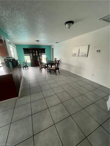 Unfurnished dining area featuring a textured ceiling and tile patterned flooring