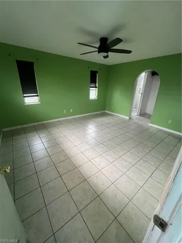 Empty room with light tile patterned flooring and ceiling fan