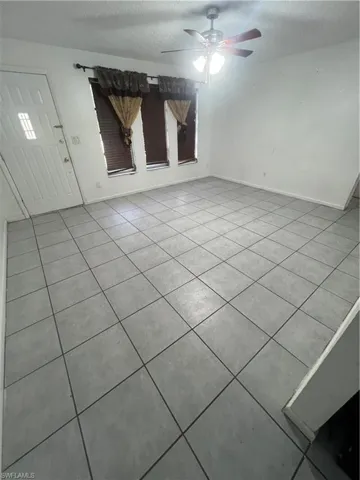 Unfurnished living room featuring ceiling fan and light tile patterned floors