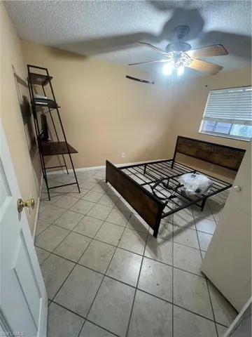 Unfurnished bedroom featuring a textured ceiling, ceiling fan, and light tile patterned floors